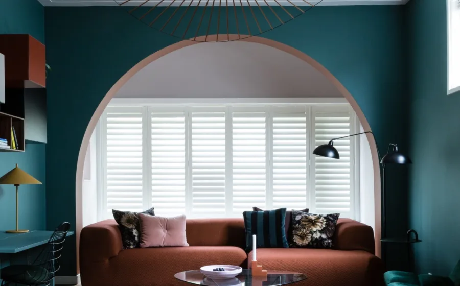 Hotel chique interieur met luxe bankstel en witte shutters als raamdecoratie.
