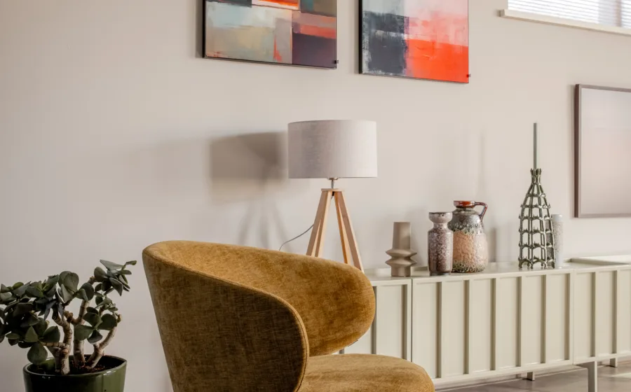 Abstracte kunst aan de muur met woonkamer lamp voor sfeerverlichting bij het dressoir met vazen en beeldjes.