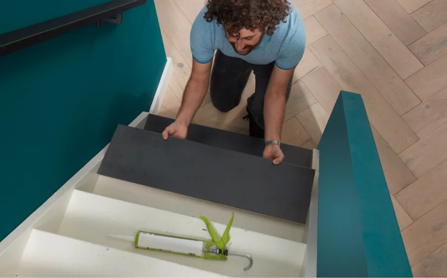 Vakman legt donker grijze overtrede op witte trap