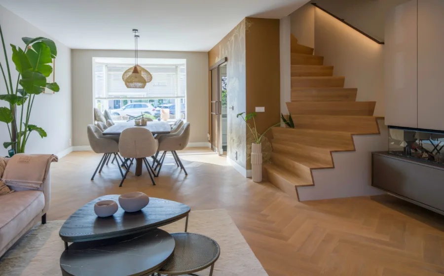 Woonkamer met visgraat vloer, haard, zithoek en Z-trap design trap met LED trapverlichting.