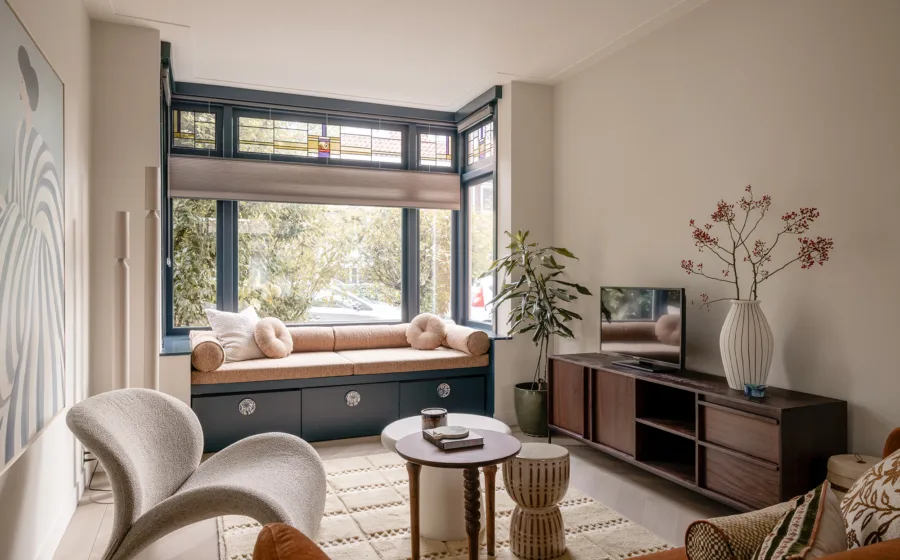 Woonkamerinterieur met zitplek in erker en raamdecoratie op maat in natuurlijke kleur.