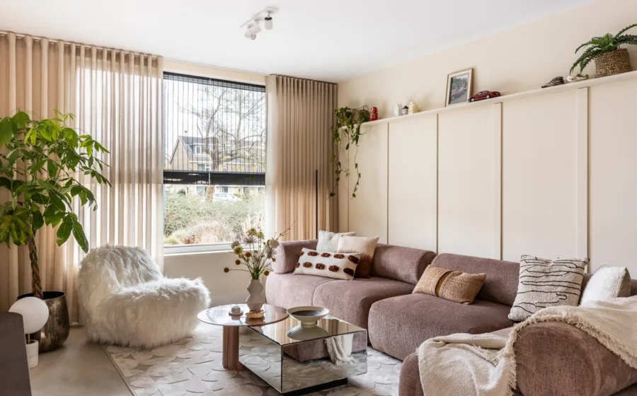 Gezellige zithoek met dubbele raamdecoratie: vitrage en geweven hout rolgordijnen.