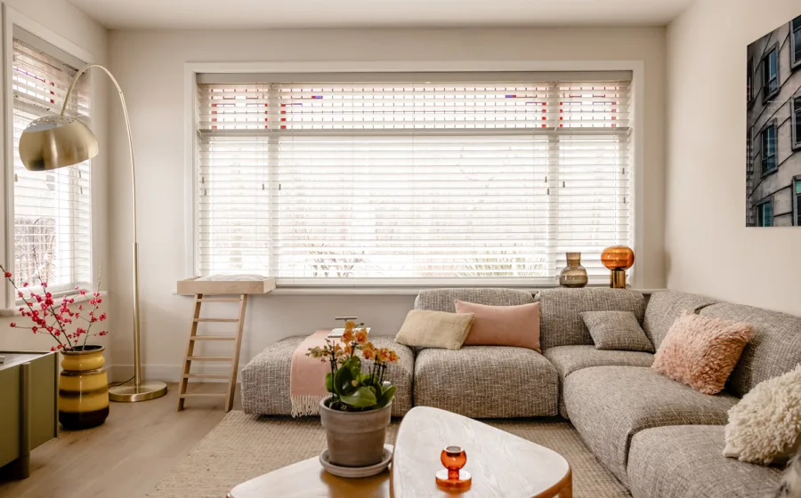 Knusse woonkamer met horizontale jaloezieën voor glas in lood ramen.