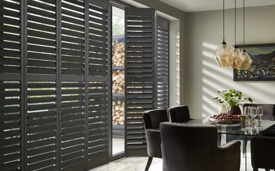 Zwart-beige interieur met zwarte shutters voor schuifpui en steenlook vloertegels.