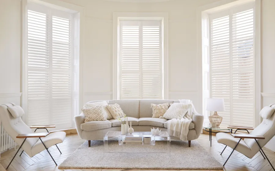 Klassiek interieur met witte shutters voor hoge ramen en sierlijke meubels