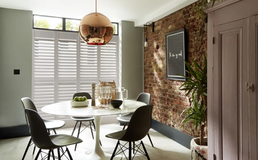 Retro interieur met brede witte shutters en ronde eettafel