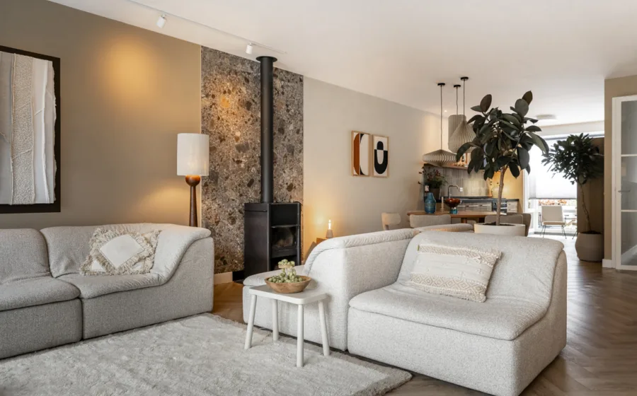 Klassieke woonkamer met matte beige en off-white muurverf, kachel met steenlook tegels.