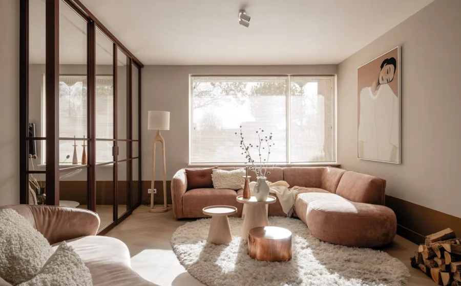 Woonkamer met lage lambrisering in warme oker tint, beige muurverf en hoekbank