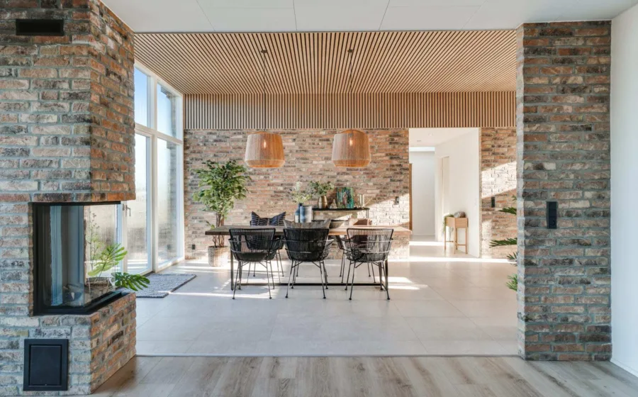 Eetkamer met bakstenen muur gecombineerd met lichte kleur wandpanelen aan het plafond