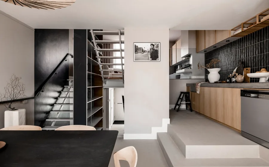 Open keuken met glanzende donkere tegels en hal met donkere muurverf.