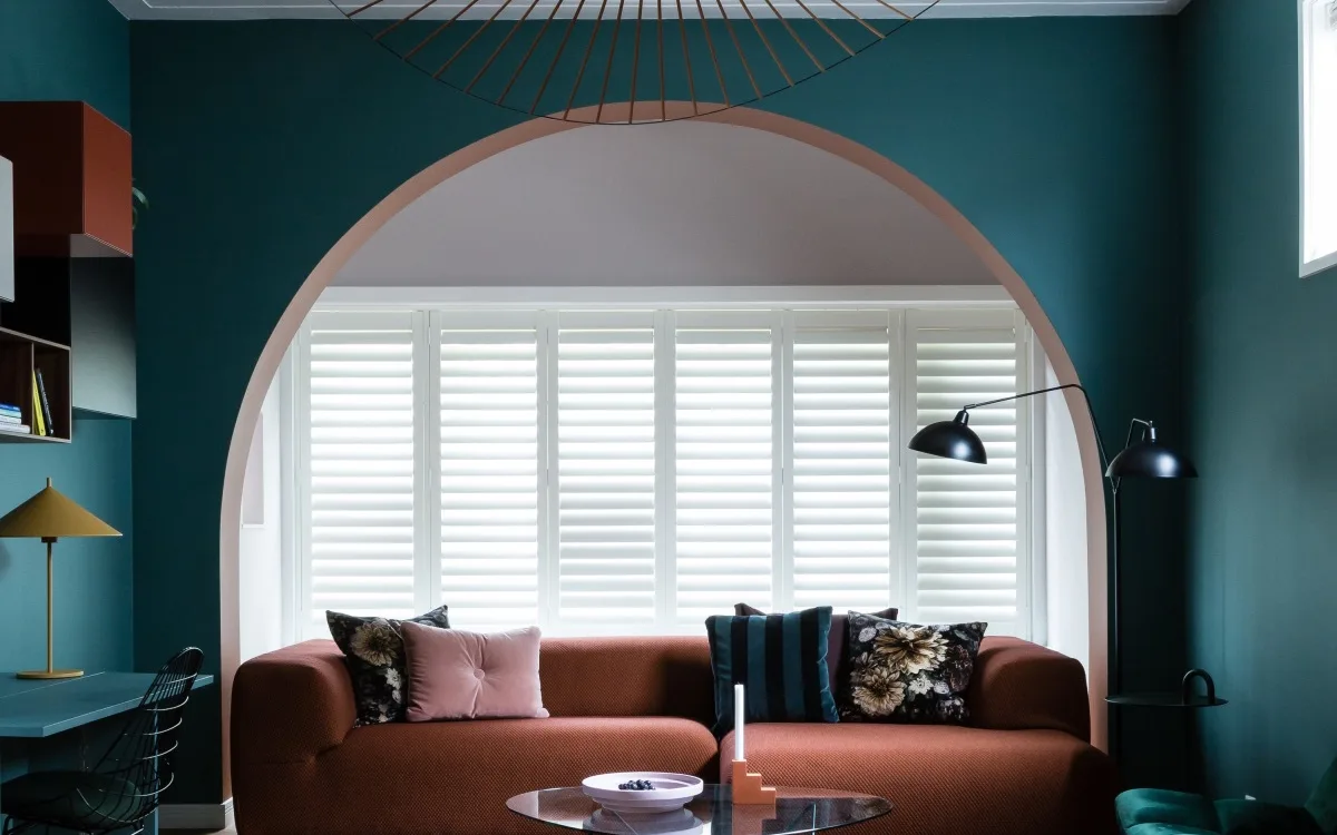 Hotel chique interieur met luxe bankstel en witte shutters als raamdecoratie.