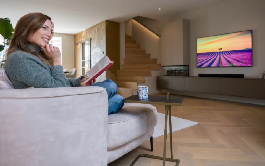 Vrouw in woonkamer met visgraat vloer, Z-trap, led-grip en tvmeubel op maat