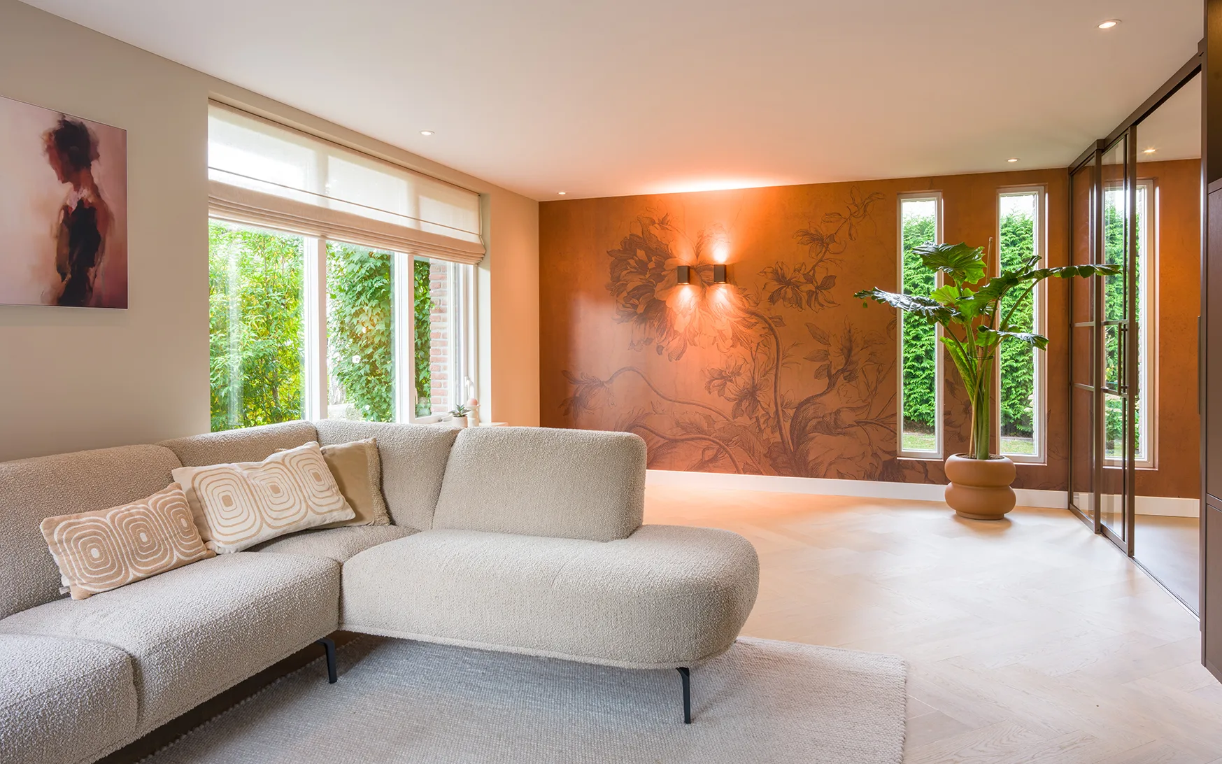 Woonkamer met visgraaat Lindura vloer, hoekbank, witte vouwgordijnen en roestrood behang van Kek