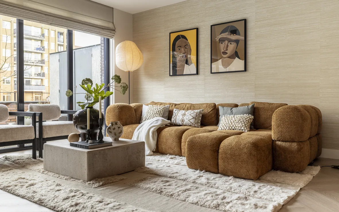 Woonkamer met structuurbehang in zachte beigetint en kunst op de muur.