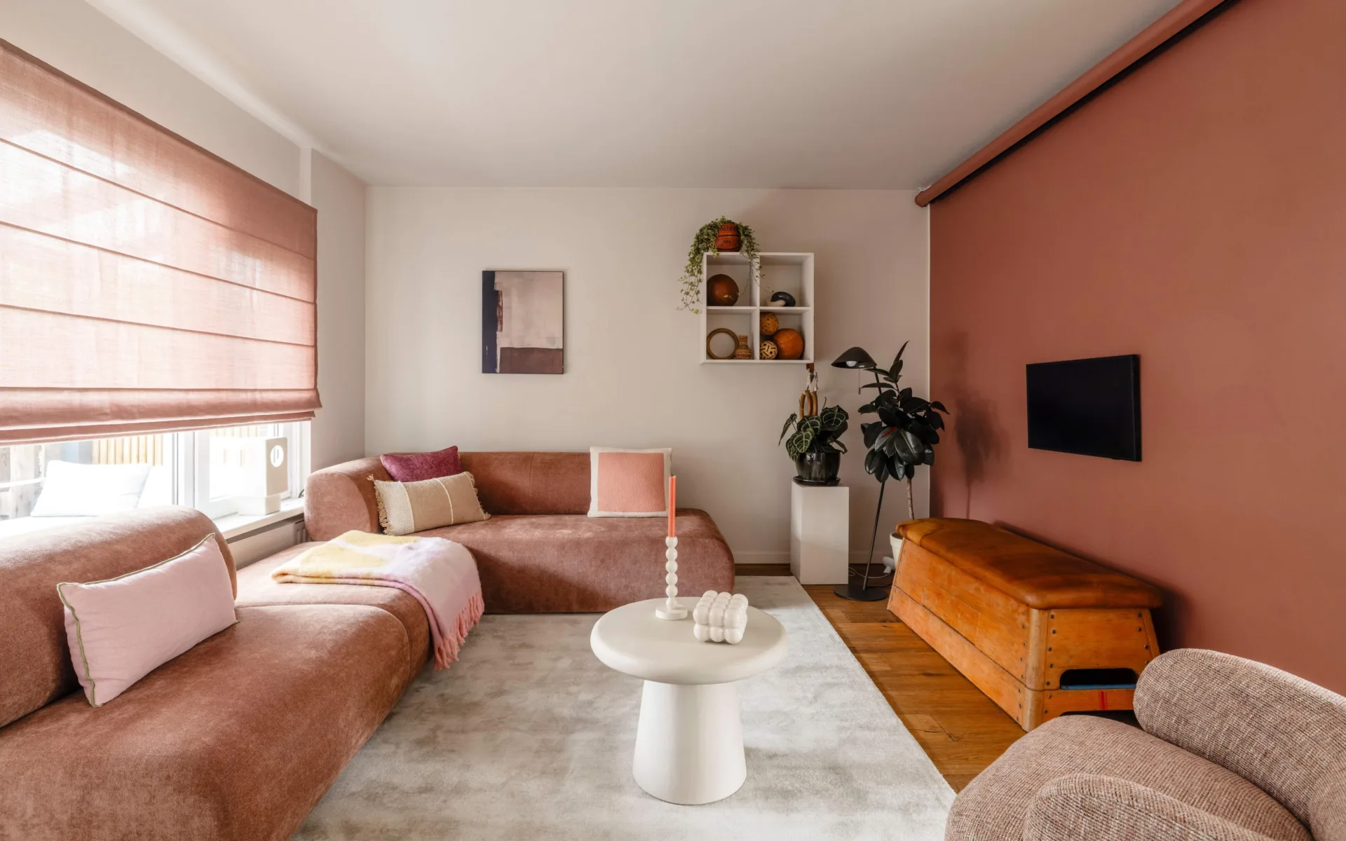 Warm kleurrijk interieur met oude roze vouwgordijnen in woonkamer met roze bank en roest muur