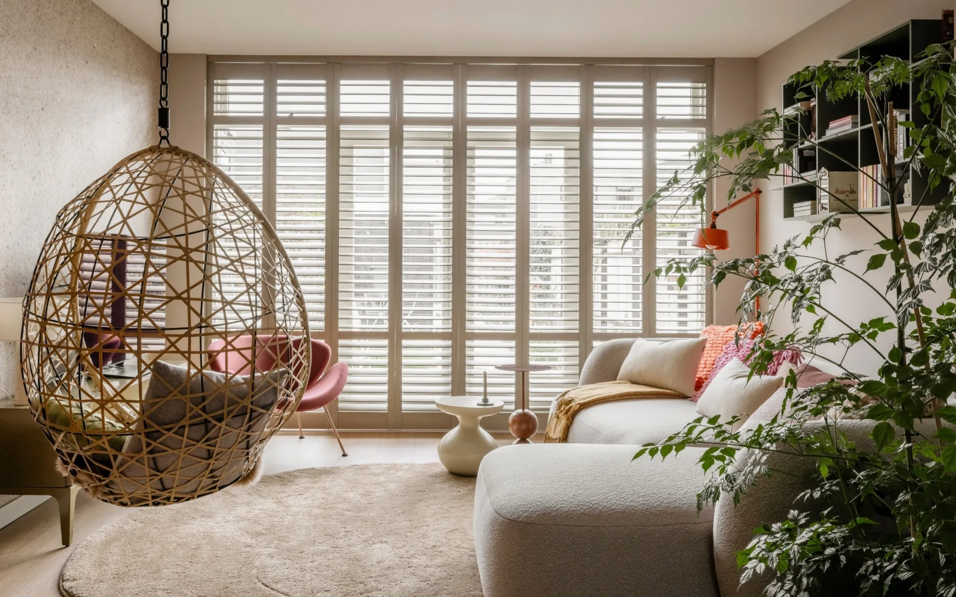 Warm kleurrijke woonkamer met pvc-vloer, vloerkleed en witte shutters