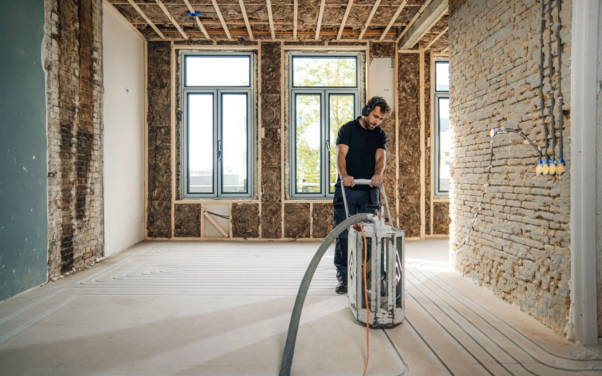 Man die een droogbouwvloer aan het inslijpen is