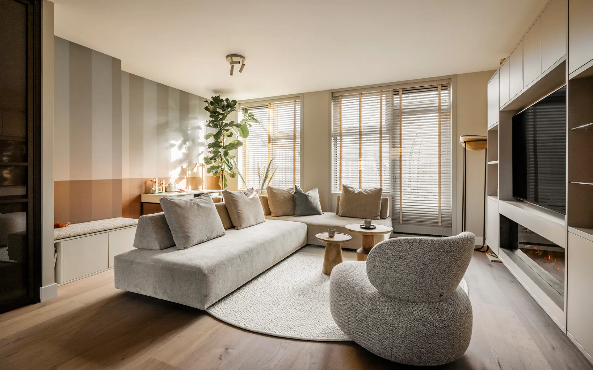 lichte woonkamer met lichte kast op maat, houten vloer en houten jaloezieën