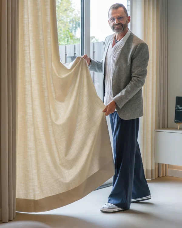 Frans Uyterlinde in de woonkamer met beige Inside gordijnen