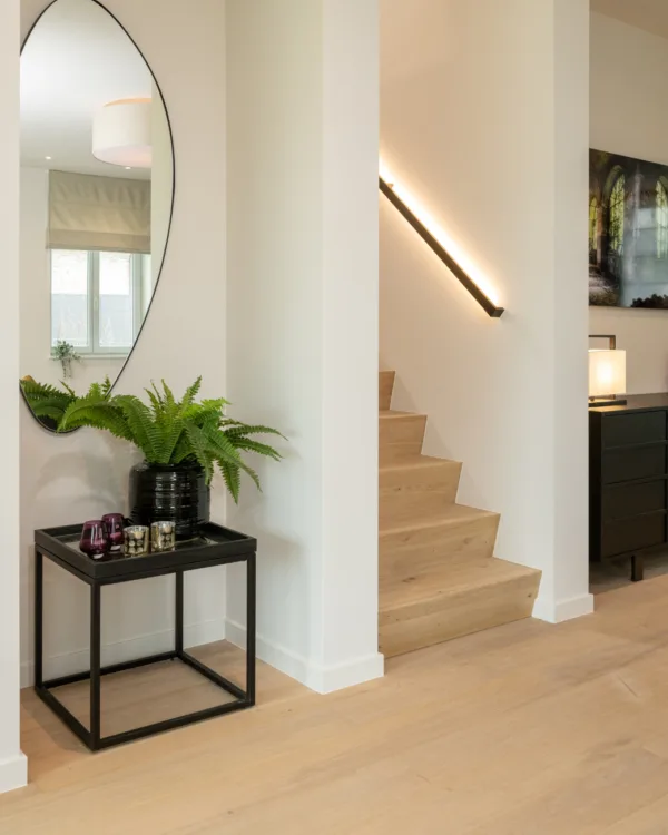 Hal met eikenhouten vloer en trap in moderne stijl en daarbij passende led trapleuning op maat.