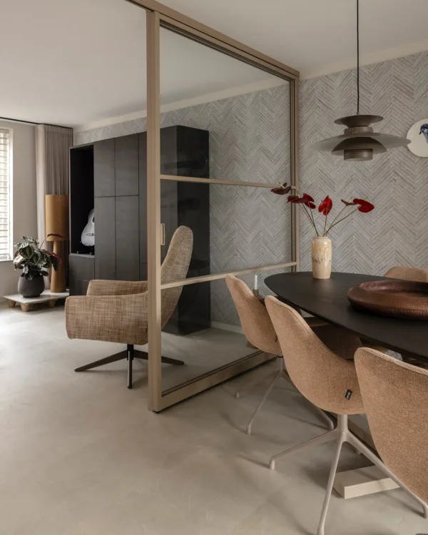 Woonkamer met betonlook tegels, stalen deuren en ovale eettafel