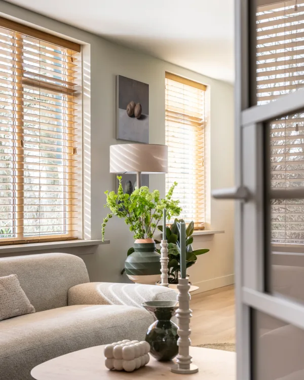 Sfeervol woonkamerinterieur met horizontale jaloezieën voor grote ramen.