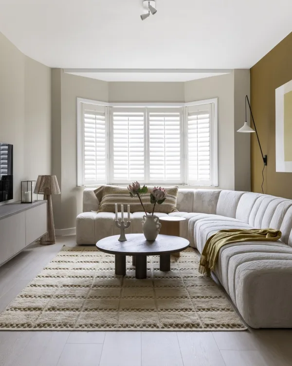 Woonkamer met erker en witte shutters op maat.