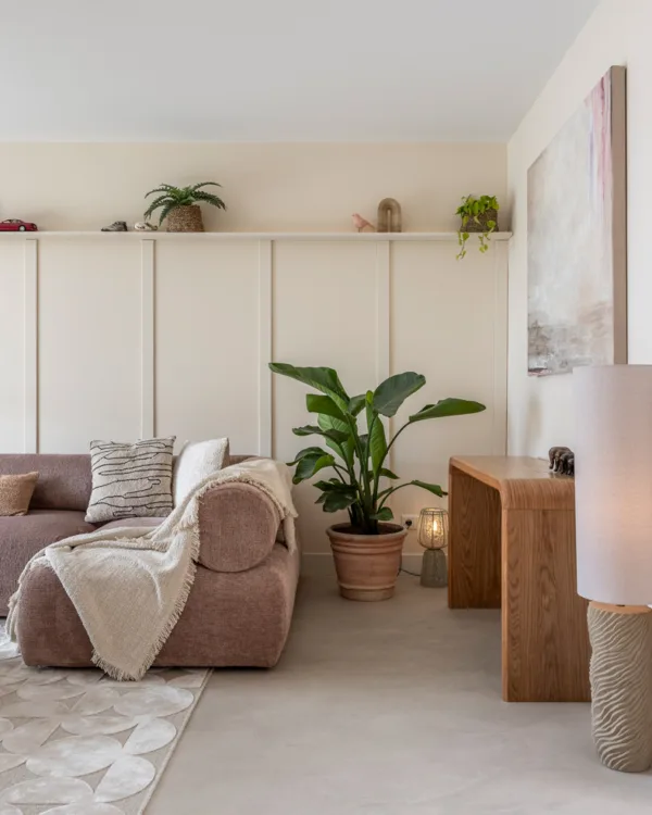 Woonkamer met lichtgrijze betonlook vloer en zachtroze bank