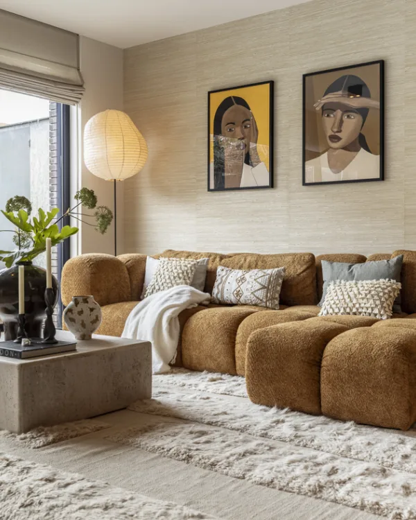 Woonkamer met structuurbehang in zachte beigetint en kunst op de muur.