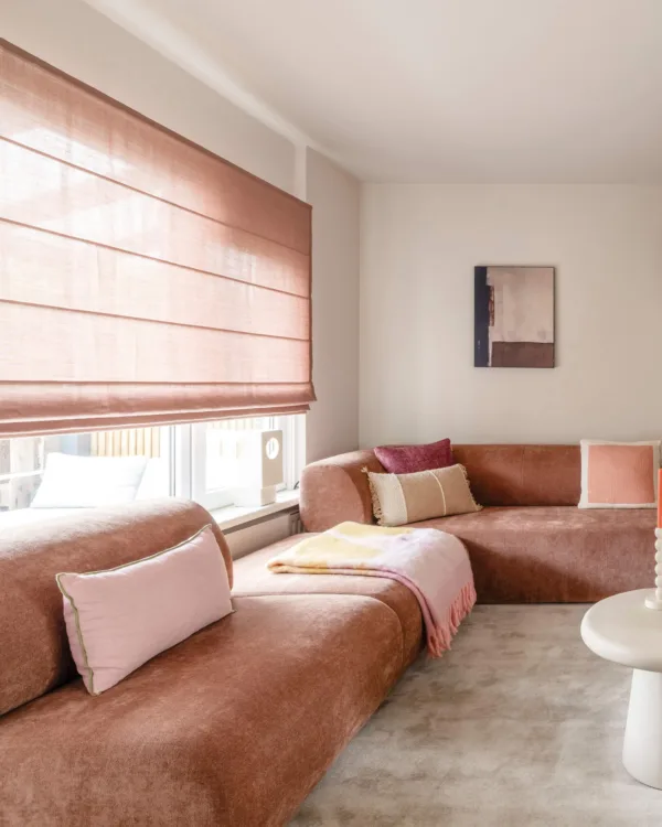 Warm kleurrijk interieur met oude roze vouwgordijnen in woonkamer met roze bank en roest muur