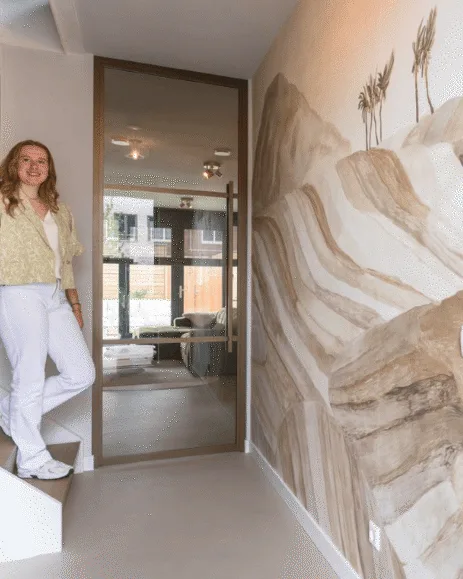 Hal met gietvloer, bronzen stalen deur en zandkleurig behang