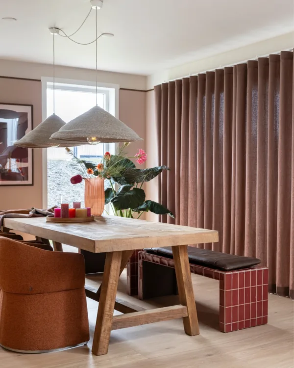 Warm kleurrijk interieur in eetkamer met warme houten vloer en donker rode/bruine inbetweengordijnen