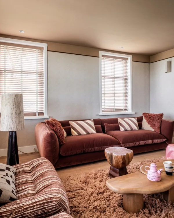 Warmkleurijke woonkamer met fluffy vloerkleed en houten jaloezieën
