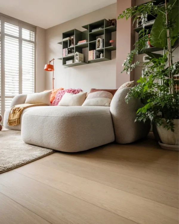 Warm kleurrijke woonkamer met lichte houtlook pvc-vloer, vloerkleed en witte shutters