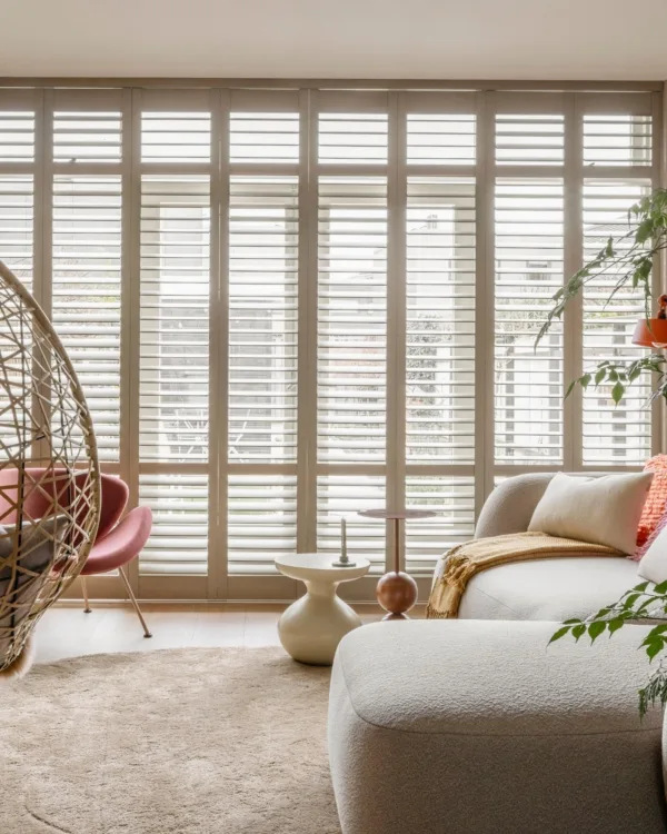 Warm kleurrijke woonkamer met pvc-vloer, vloerkleed en witte shutters