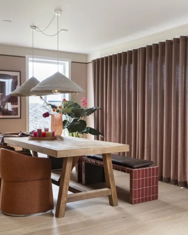 Gezellige eetkamer met bankje, robuuste houten tafel en zachte overgordijnen