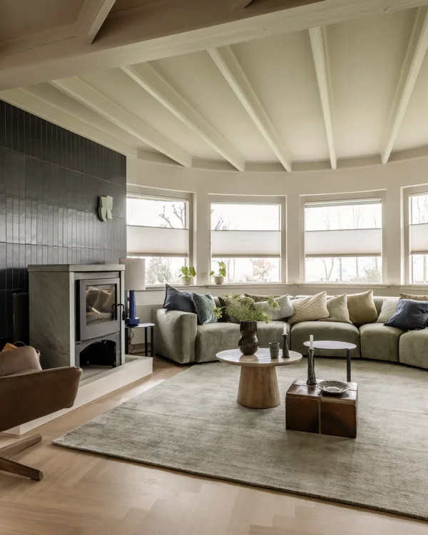Woonkamer met witte duette shades op maat, fineerparket vloer en ovale bank