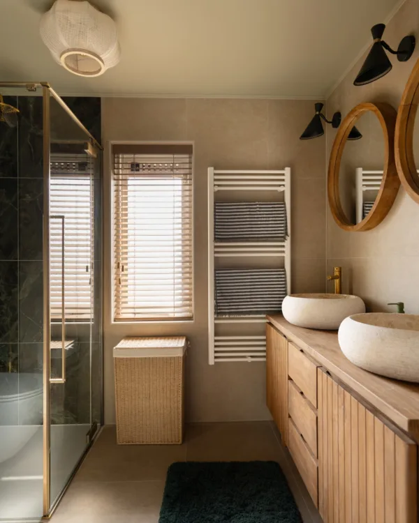 Luxe badkamer met mix van marmer, hout en messing accenten.