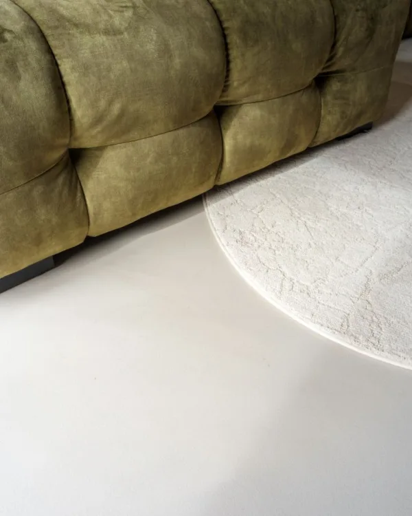 Corestone Nature Blend gietvloer in de kleur Summer beach met een groene bank en rond vloerkleed