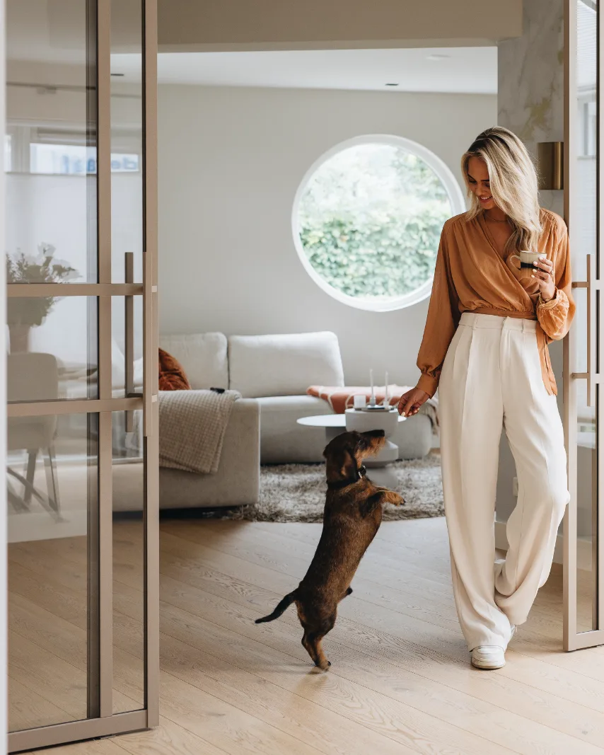 Beige stalen deuren, houten vloer in woonkamer met vrouw en hond