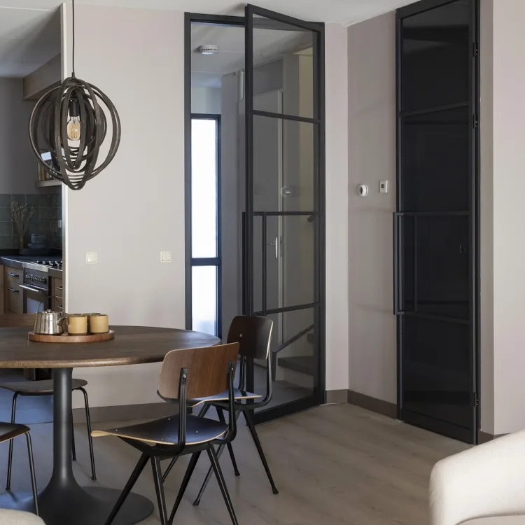 Strakke en moderne woonkamer met een grijsbruine laminaatvloer en een glazen stalen deur.