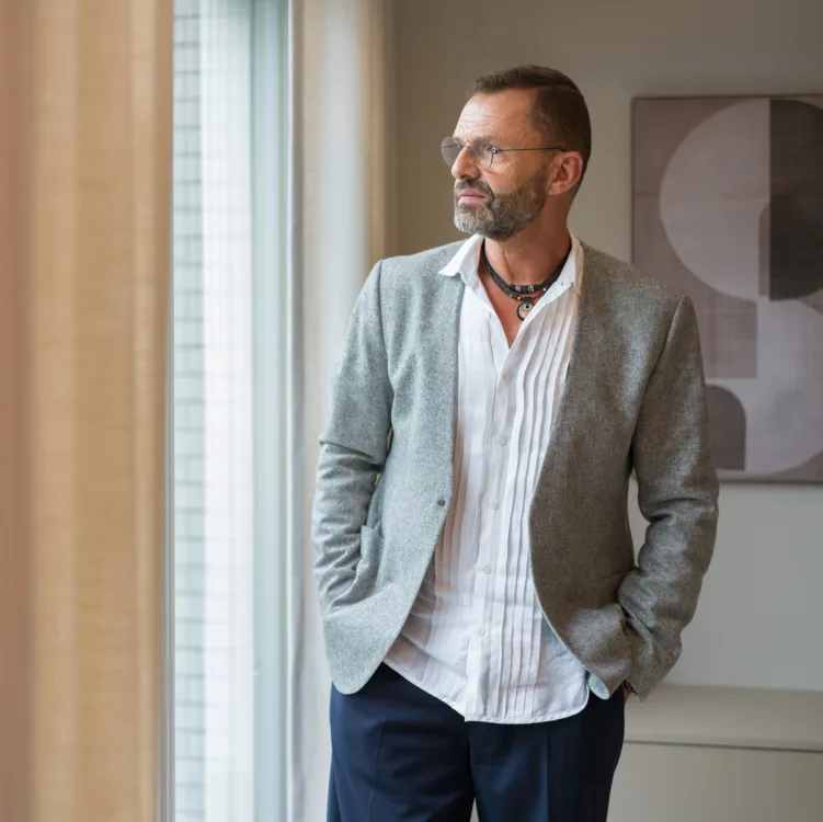 Portretfoto van Frans Uyterlinde bij de gordijnen van Inside in de woonkamer