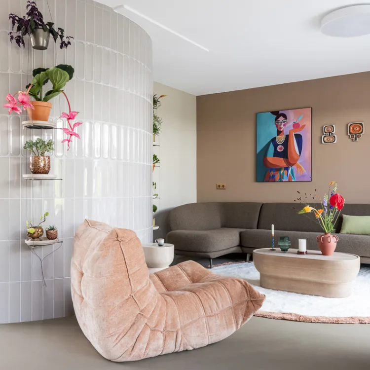 Moderne woonkamer met lichtgrijze gietvloer, grote hokbank en superzacht vloerkleed.