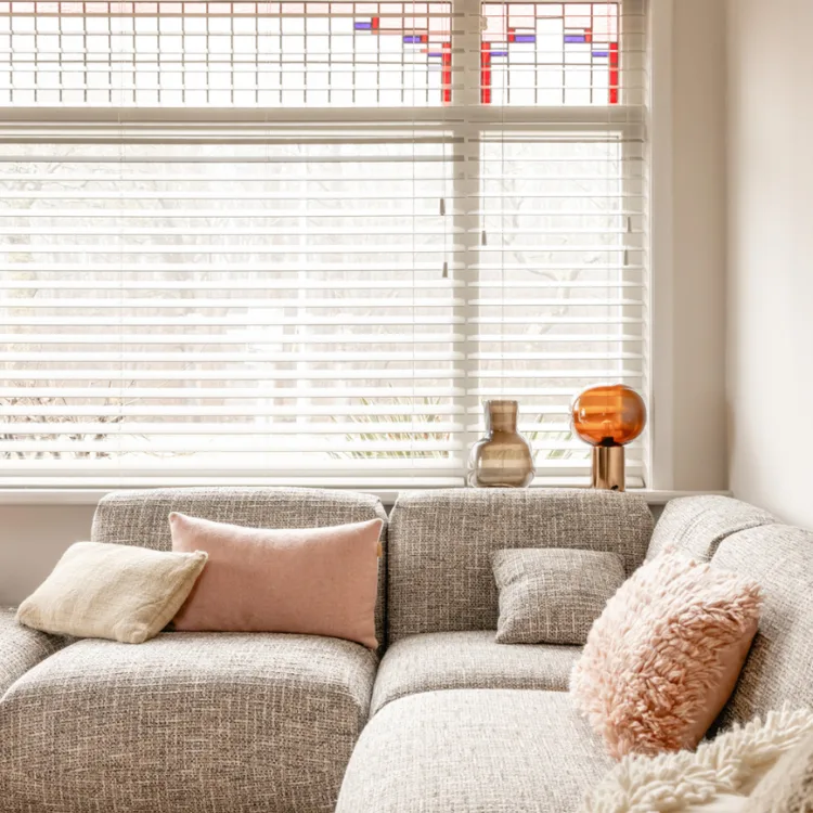 Sfeerfoto van een basic naturel woonkamer met witte horizontale jaloezieën