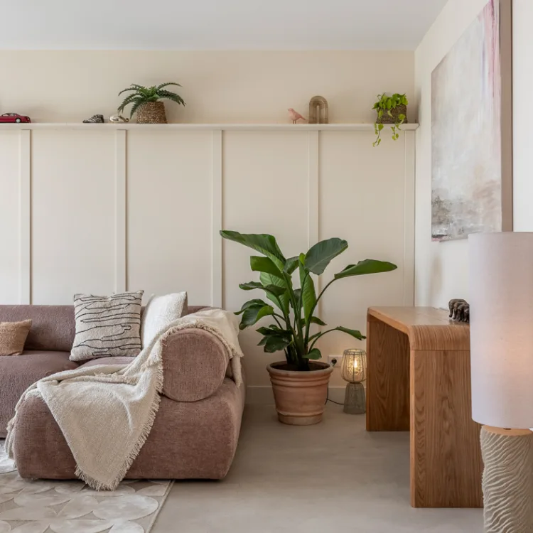 Woonkamer met lichtgrijze betonlook vloer en zachtroze bank