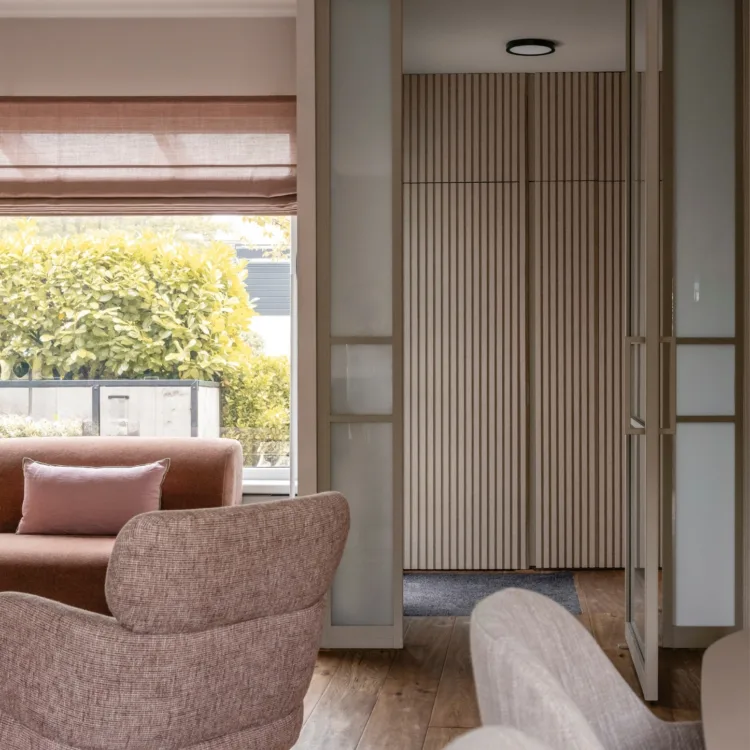 Warm kleurrijk interieur met oude roze vouwgordijnen in woonkamer met roze fateuil en lichte stalen deuren