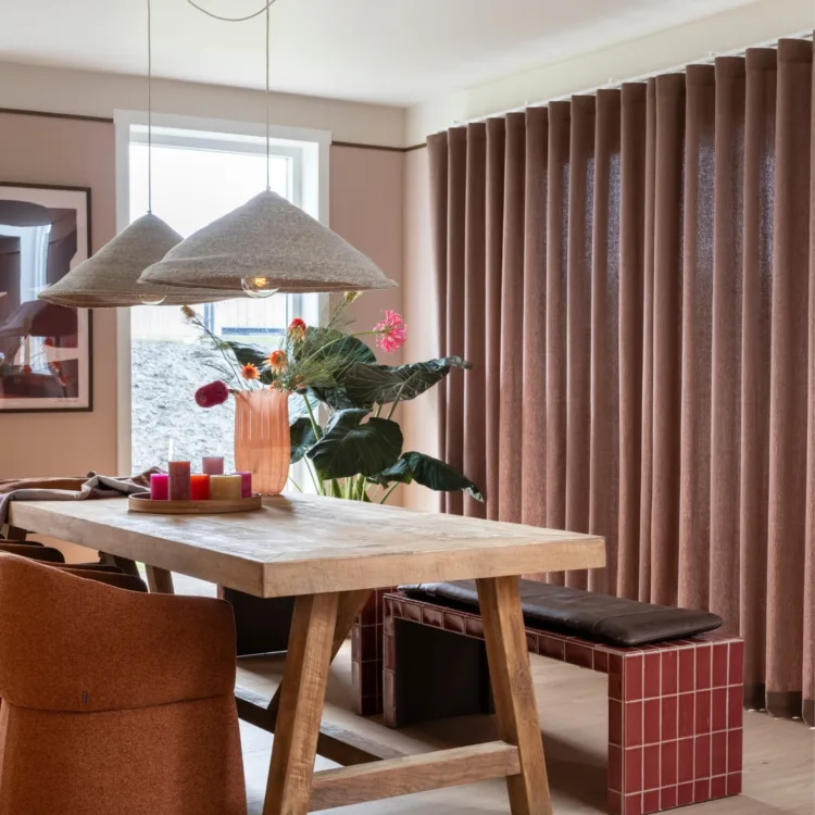 Warm kleurrijk interieur in eetkamer met warme houten vloer en donker rode/bruine inbetweengordijnen