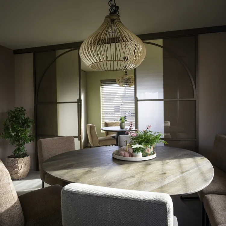 Kamer met stalen deuren met boog en een ovale tafel met gestoffeerde stoelen en bankje