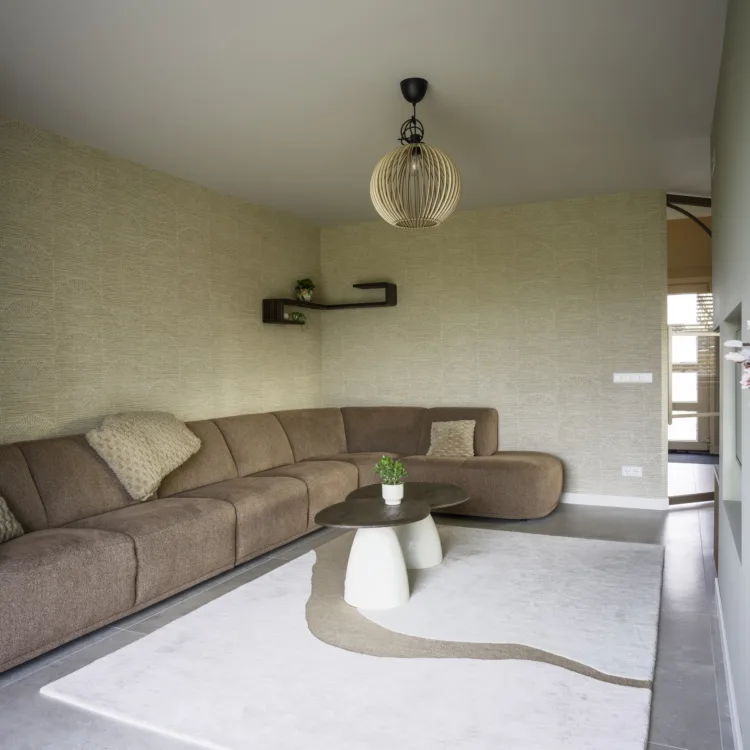 Woonkamer met royale bank, rechthoekig vloerkleed en pastelkleurig behang