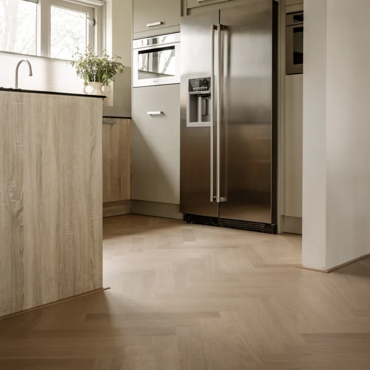 Moderne keuken met strakke lijnen en harmonieus lichtinval door slimme raamdecoratie en de natuurlijke, houten vloer.